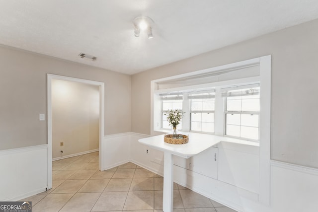 dining room featuring light tile patterned floors, visible vents, and a wainscoted wall