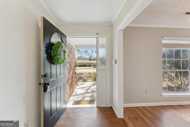 entrance foyer featuring a textured ceiling, crown molding, baseboards, and hardwood / wood-style floors