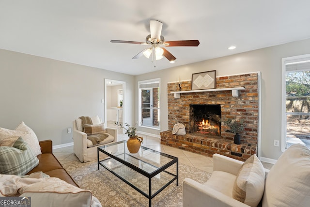 living room with light tile patterned floors, baseboards, a brick fireplace, and ceiling fan