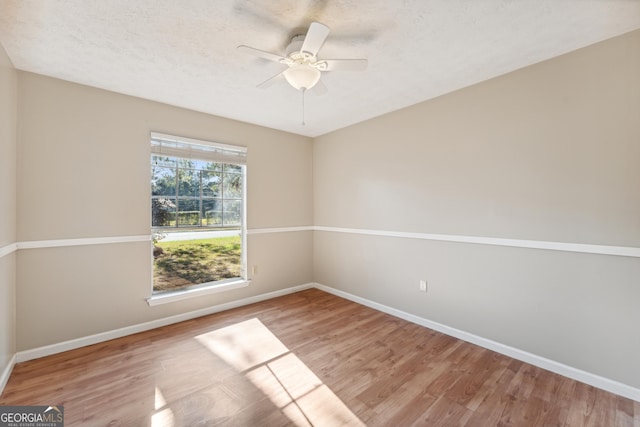 unfurnished room with a textured ceiling, a ceiling fan, baseboards, and wood finished floors