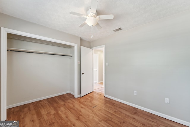 unfurnished bedroom with visible vents, baseboards, light wood-style floors, a closet, and a textured ceiling