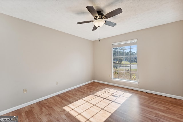 unfurnished room with ceiling fan, baseboards, a textured ceiling, and wood finished floors