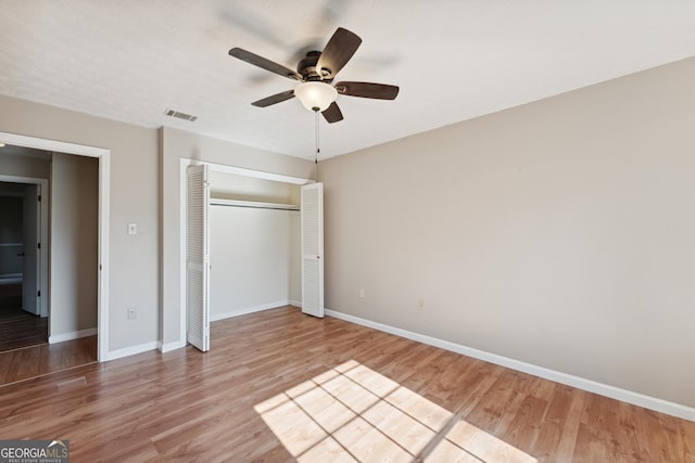 unfurnished bedroom featuring visible vents, baseboards, wood finished floors, a closet, and a ceiling fan