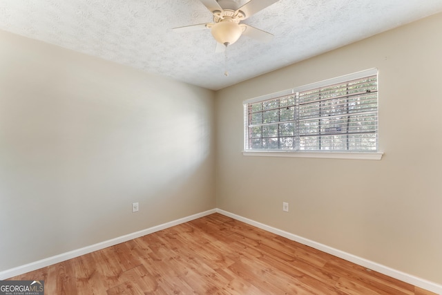 empty room with a ceiling fan, light wood-style floors, baseboards, and a textured ceiling