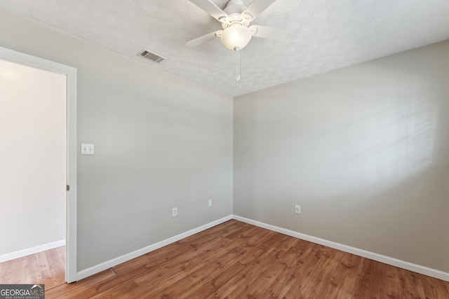 spare room featuring visible vents, baseboards, wood finished floors, a textured ceiling, and a ceiling fan