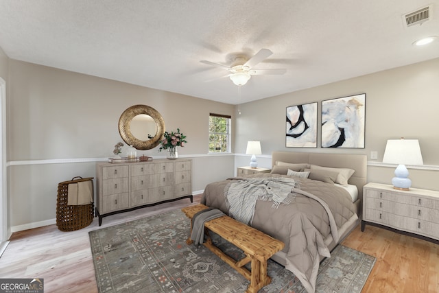 bedroom with visible vents, baseboards, light wood-style floors, and a ceiling fan