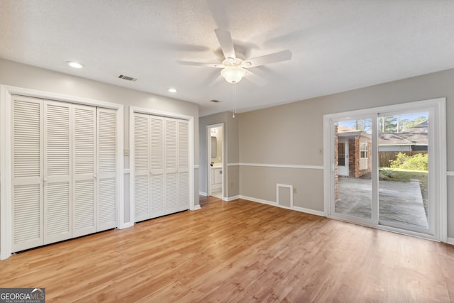 unfurnished bedroom with light wood-type flooring, visible vents, two closets, access to outside, and baseboards