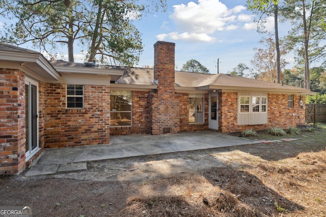 rear view of property featuring a patio area, brick siding, and a chimney