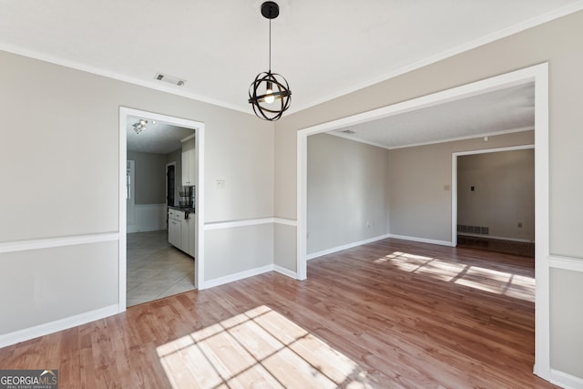 empty room with crown molding and light hardwood / wood-style floors