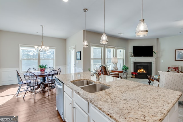 kitchen featuring sink, hanging light fixtures, stainless steel dishwasher, white cabinets, and light wood-type flooring