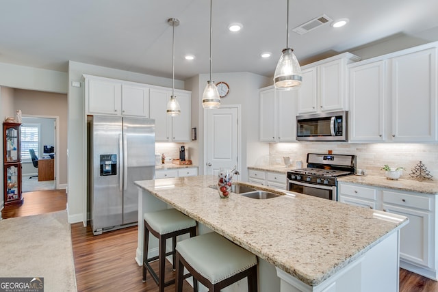 kitchen featuring white cabinets, appliances with stainless steel finishes, and a center island with sink