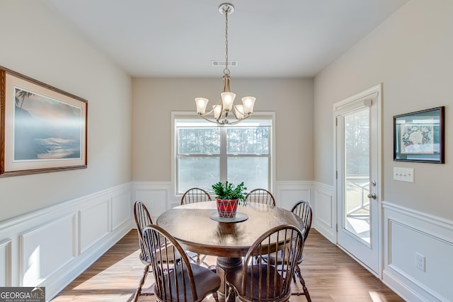 4336 Rockrose Green Way, Gainesville, GA 30504 - dining space featuring a chandelier, light wood-style floors, a decorative wall, and wainscoting