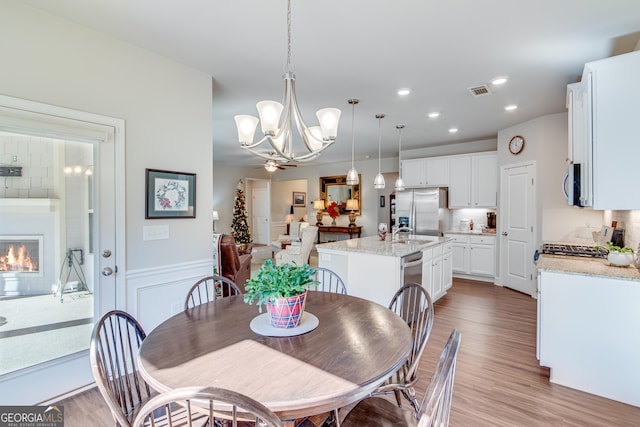 dining area featuring ceiling fan with notable chandelier, light wood-type flooring, and sink