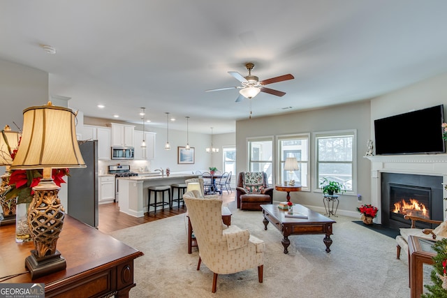 living room with light hardwood / wood-style floors, ceiling fan, and sink