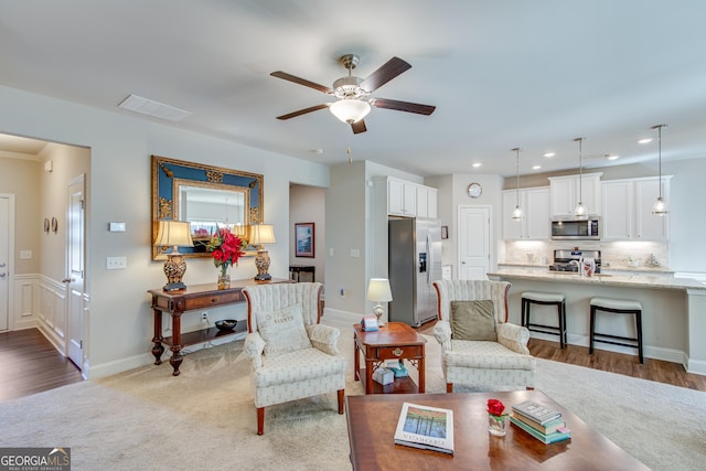 living room featuring ceiling fan, light hardwood / wood-style flooring, and sink