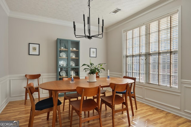 dining room featuring light hardwood / wood-style flooring, a wealth of natural light, and ornamental molding