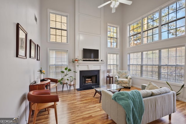 260 Wildcat Lake Dr, Lawrenceville, GA 30043 - living room with a high ceiling, healthy amount of natural light, a ceiling fan, a fireplace with flush hearth, and light wood-style floors