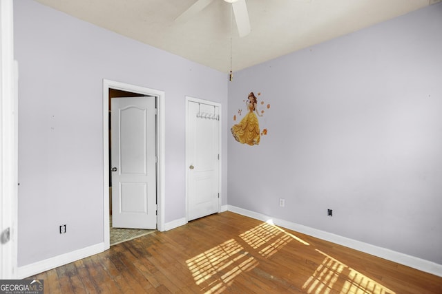 unfurnished bedroom featuring dark hardwood / wood-style flooring, ceiling fan, and a closet