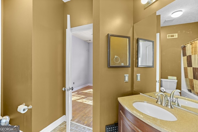 bathroom featuring walk in shower, vanity, toilet, and a textured ceiling