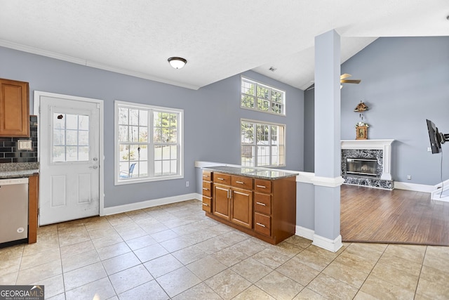 kitchen featuring lofted ceiling, light tile patterned floors, a fireplace, and dishwasher