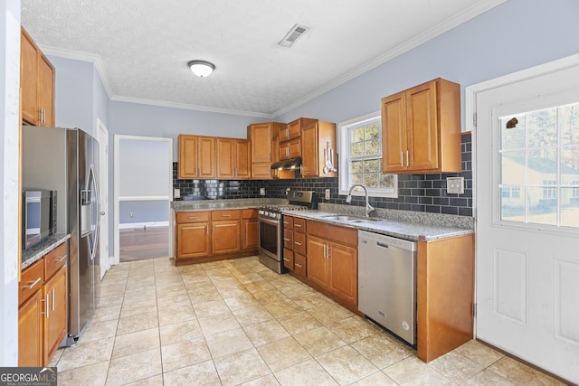 kitchen with sink, crown molding, light tile patterned floors, appliances with stainless steel finishes, and a healthy amount of sunlight