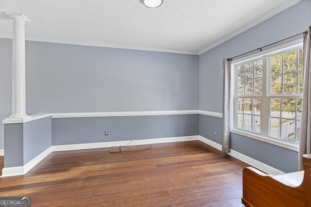 interior space featuring ornamental molding, dark hardwood / wood-style floors, a textured ceiling, and ornate columns