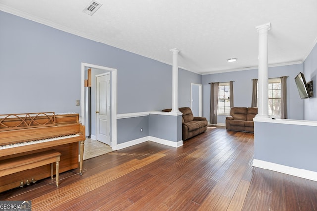 living room with decorative columns, crown molding, and hardwood / wood-style floors