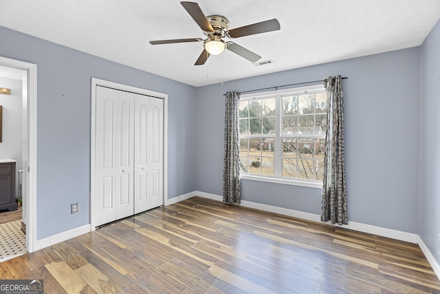 unfurnished bedroom with wood-type flooring, ceiling fan, and a closet