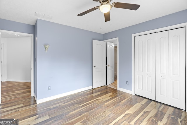 unfurnished bedroom featuring ceiling fan, dark hardwood / wood-style floors, and a closet