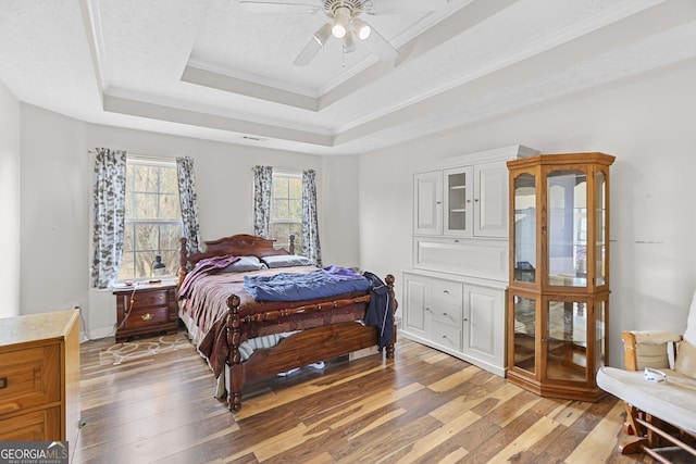 bedroom featuring crown molding, ceiling fan, a raised ceiling, and hardwood / wood-style flooring