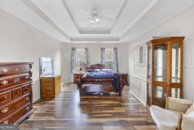 bedroom featuring crown molding, a textured ceiling, a tray ceiling, dark hardwood / wood-style flooring, and ceiling fan