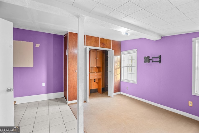 unfurnished bedroom with light tile patterned floors and beamed ceiling