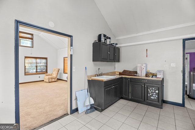 kitchen with vaulted ceiling, sink, water heater, and light tile patterned floors