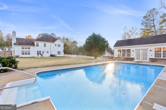 view of swimming pool featuring an outdoor structure, a lawn, and french doors