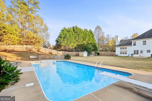 view of swimming pool featuring a shed, a yard, a patio area, and a diving board