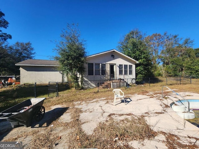 rear view of property featuring a patio and a fenced in pool