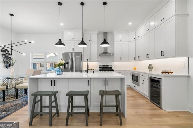 kitchen with white cabinets, wine cooler, hanging light fixtures, and appliances with stainless steel finishes