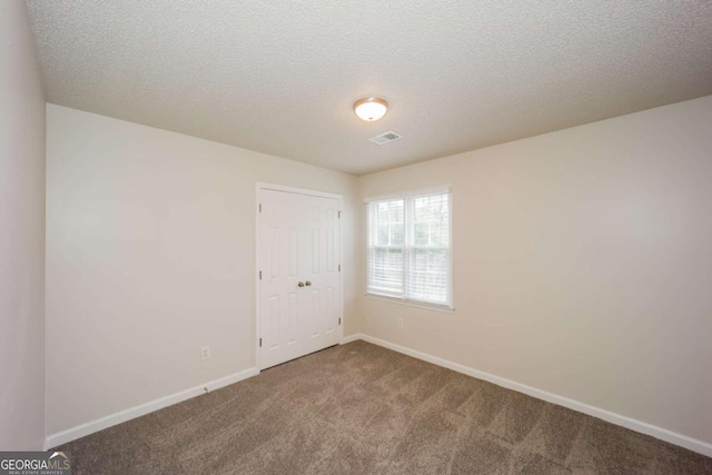 empty room with carpet floors and a textured ceiling