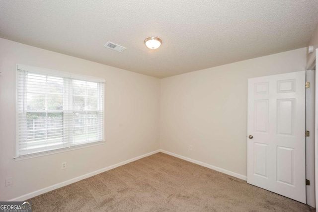 carpeted empty room featuring a textured ceiling