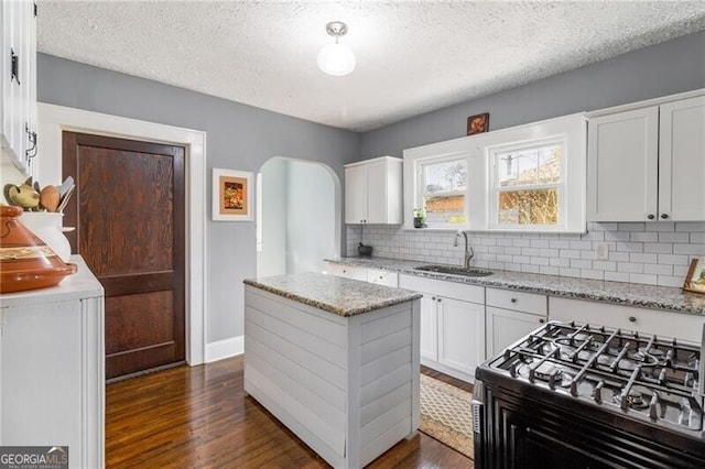 kitchen featuring dark hardwood / wood-style flooring, light stone counters, stainless steel range, sink, and white cabinetry