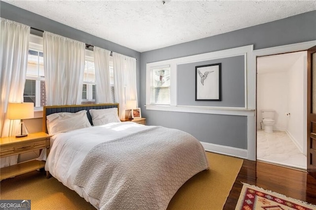 bedroom with a textured ceiling, hardwood / wood-style flooring, and ensuite bathroom