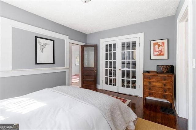 bedroom with a textured ceiling, dark wood-type flooring, and french doors