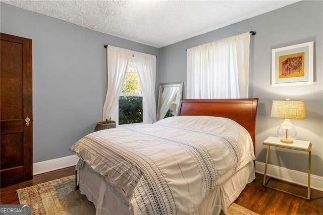 bedroom featuring a textured ceiling and dark hardwood / wood-style flooring