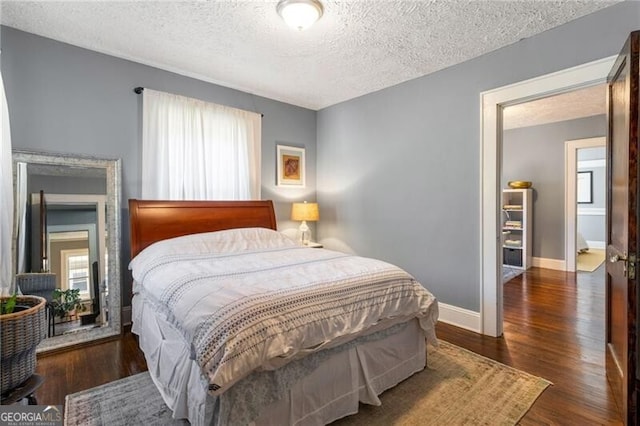 bedroom with dark hardwood / wood-style flooring, a textured ceiling, and multiple windows