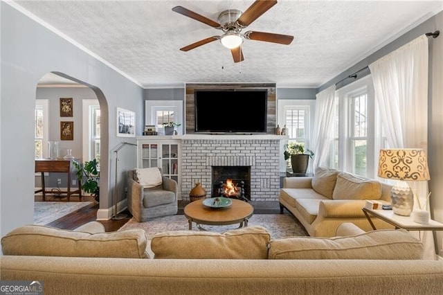 living room with ceiling fan, a fireplace, wood-type flooring, and a textured ceiling