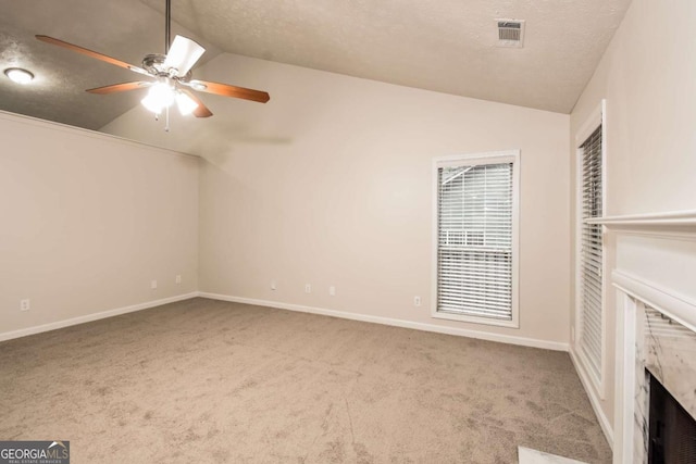 interior space featuring a textured ceiling, ceiling fan, a high end fireplace, and vaulted ceiling