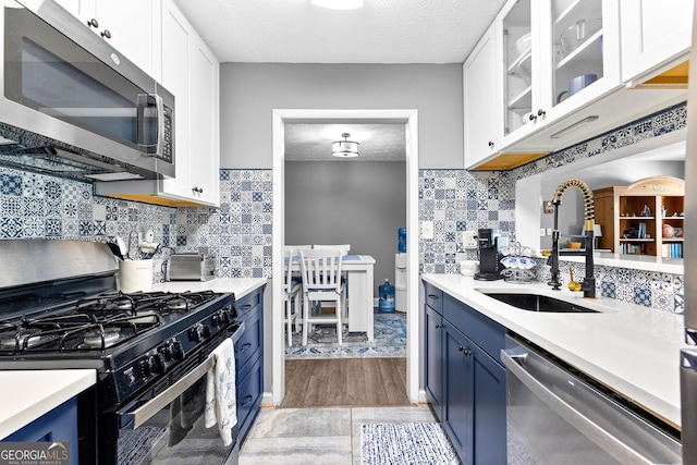 kitchen with blue cabinetry, sink, stainless steel appliances, a textured ceiling, and white cabinets