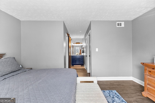 bedroom with dark hardwood / wood-style floors, a textured ceiling, and ensuite bath