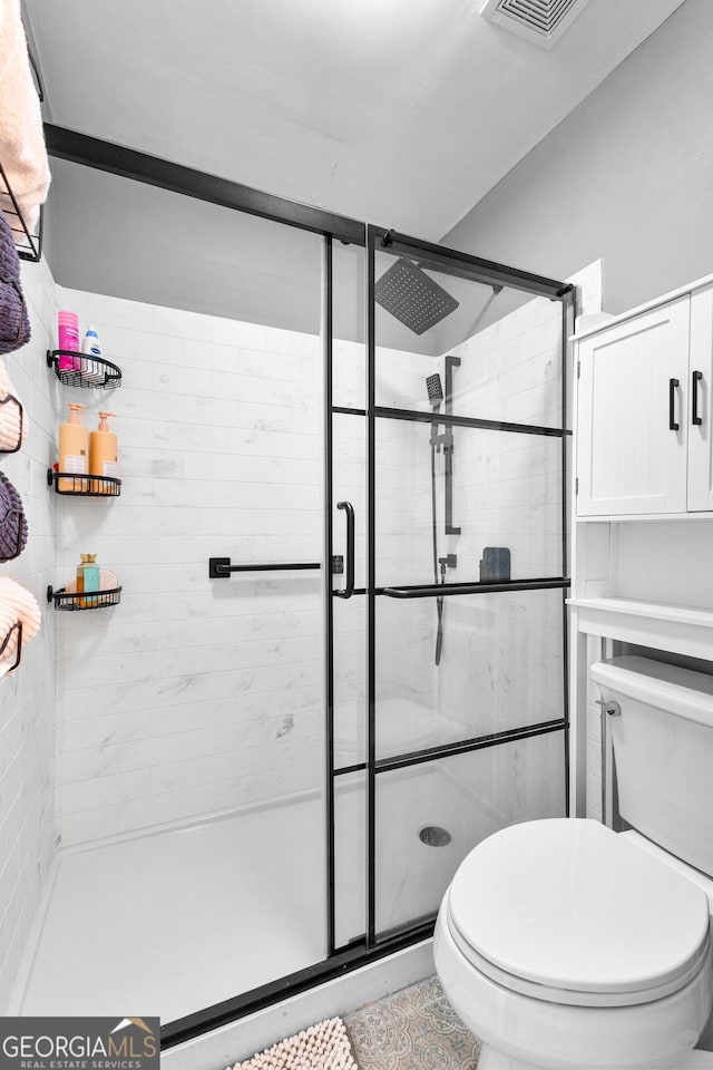 bathroom with tile patterned flooring, an enclosed shower, and toilet