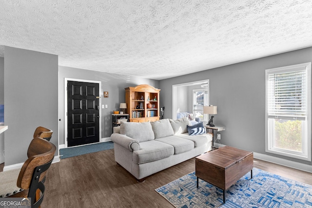 living room featuring a textured ceiling, a wealth of natural light, and dark wood-type flooring